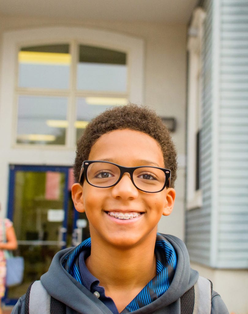 Young teen boy in braces smiling outside school